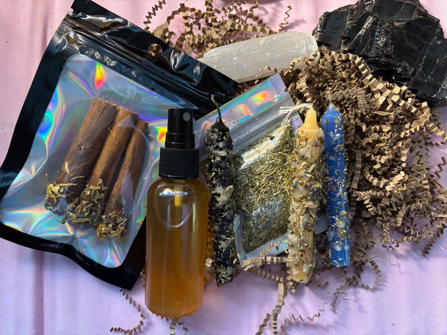 A variety of spiritual cleansing items including candles, a protection spray, incense, and a crystal.